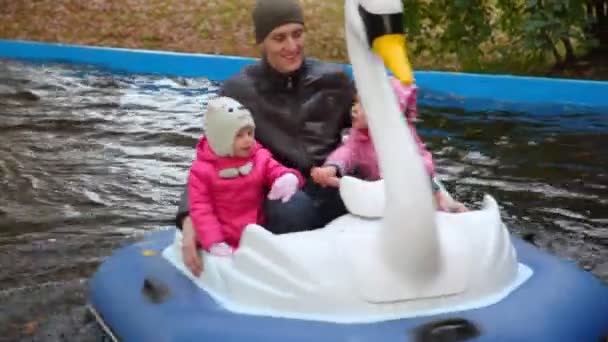Człowiek z dwoma dziewczynami siedzi w obrotowe kaczek w parku jesień — Wideo stockowe