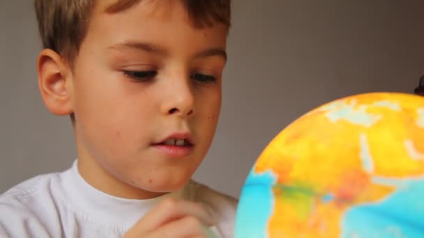 Junge sieht leuchtenden Globus an und dreht ihn drinnen aus nächster Nähe — Stockvideo