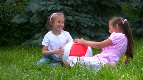 Las niñas se sienta con la pelota en la hierba en el parque y juega — Vídeos de Stock