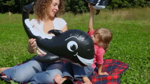 Woman and daughter plays with toy sharks in summer field — Stock Video