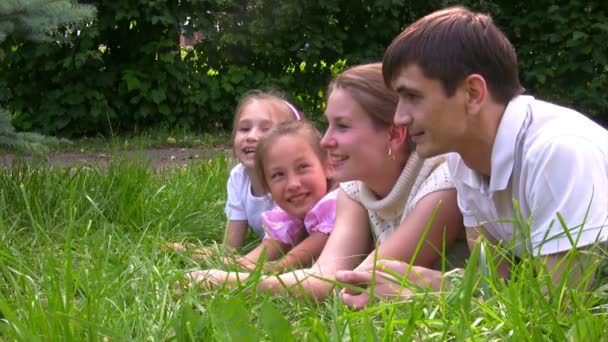 Familjen liggande på gräs i sommaren park — Stockvideo