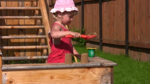 Klein meisje speelt met zand mal in playdround in de buurt van huis — Stockvideo