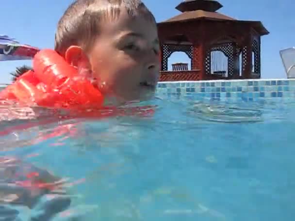 Menino na jaqueta inflável nada na piscina de água — Vídeo de Stock