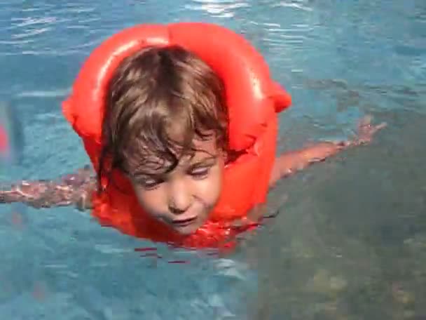 Menina em jaqueta salva-vidas nada na piscina de água ao ar livre — Vídeo de Stock