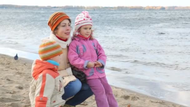 Woman with kids sits on sandy bank — Stock Video