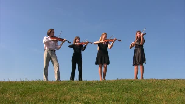 Четыре музыканта играют на скрипках на холме — стоковое видео