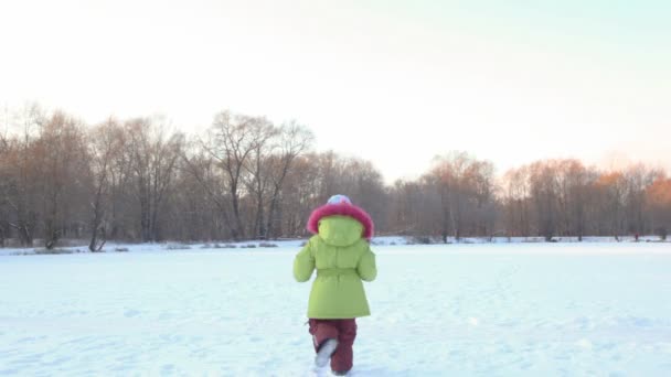 Girl runs from camera in wintry snowfield, and comes back — Stock Video