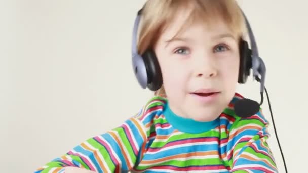 Girl in headset and striped T-shirt swings from side to side, shakes her head and sings — Stock Video