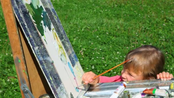 Невідомий чоловік навчає дівчину малювати літню природу — стокове відео