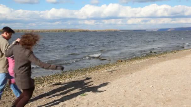 Famille courant sur la rive de la rivière — Video