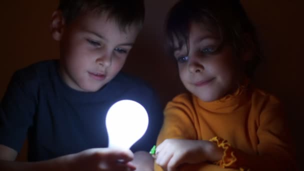 Meisje switches in- en uitschakelen gloeilamp, welke jongen in de hand houdt — Stockvideo