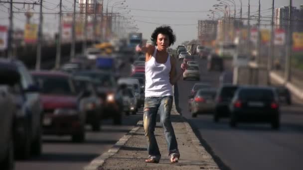 Дівчина танцює на шосе посередині міста — стокове відео