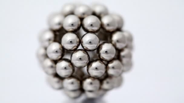 Figura constituída por esferas metálicas girar em torno de seu eixo sobre fundo branco — Vídeo de Stock