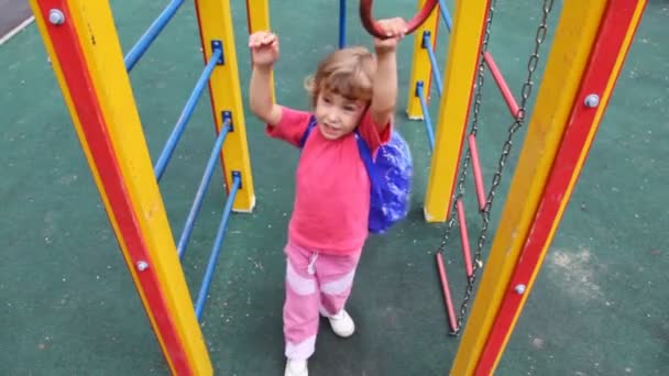 Menina no playground se aproxima de anéis e paira sobre eles — Vídeo de Stock
