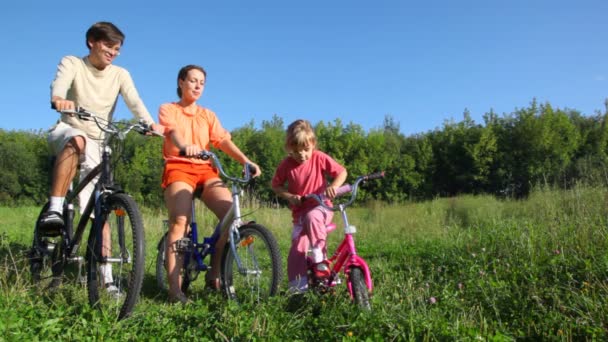 Family with daughter sits on bicycles and talks — Stock Video