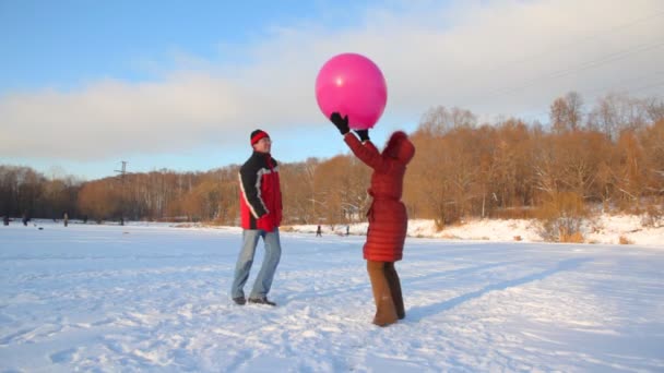 Pareja juega con globo aerostático en campo de nieve al aire libre — Vídeos de Stock