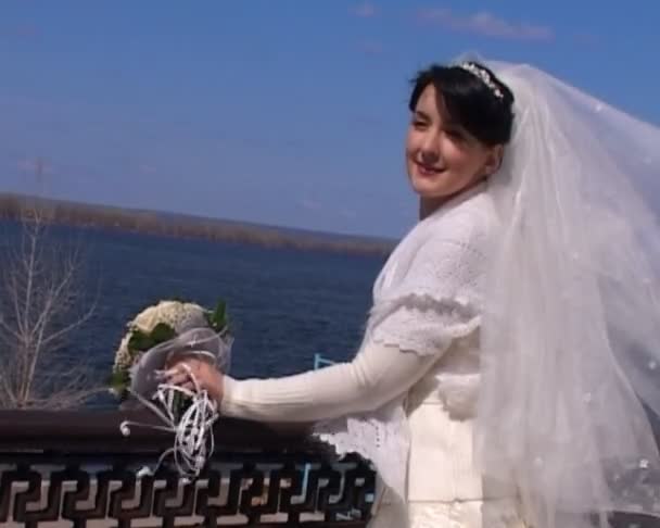 Braut mit Strauß steht gegen Fluss — Stockvideo