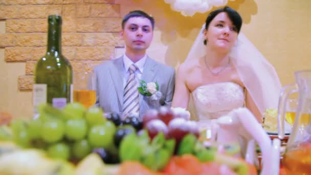 Novio y novia se sienta a la mesa de la boda — Vídeos de Stock