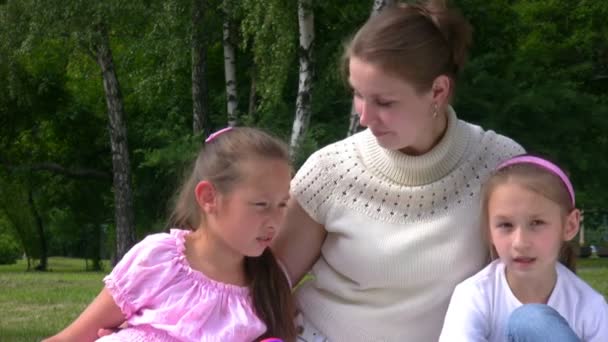 Woman and two girls sits on grass in park — Stock Video