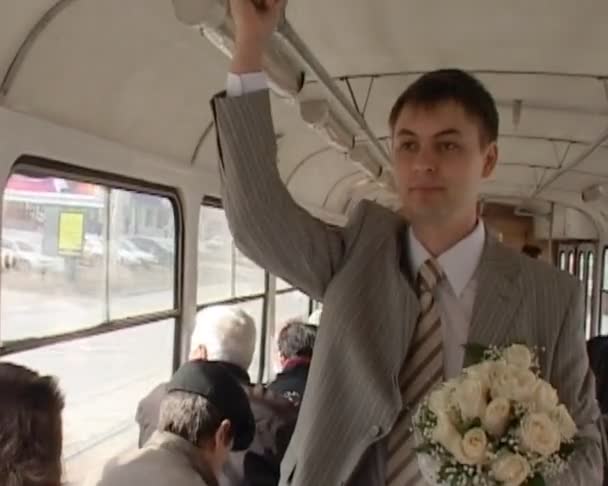 Groom avec bouquet de mariage se tient dans le bus et tient la main courante — Video