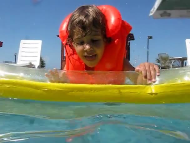 Menina no colchão inflável na piscina de água — Vídeo de Stock