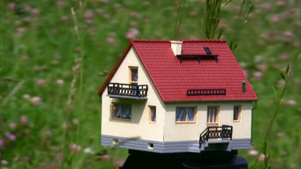 Homme main prenant maison jouet debout dans le champ 