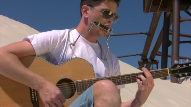 El hombre se sienta en la playa y toca la guitarra — Vídeo de stock