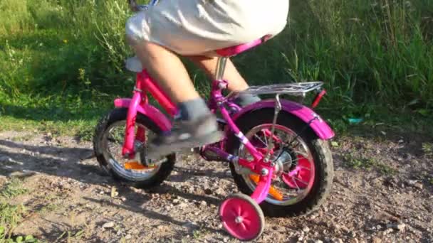 Chico pedaleando en bicicleta en el parque, chica lo empuja — Vídeos de Stock