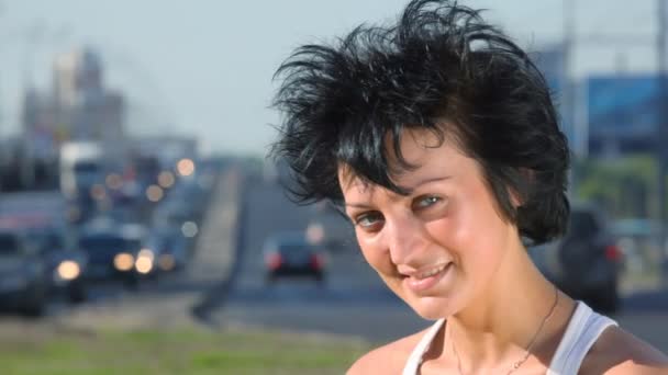 Усміхнена дівчина стоїть на шосе посередині міста — стокове відео