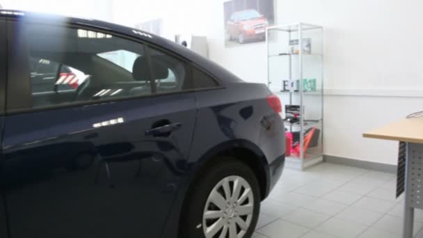 Черный блестящий новый автомобиль находится в салоне офисной машины рядом с рабочим местом — стоковое видео