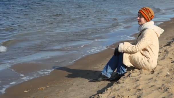 Mulher senta-se na praia de areia — Vídeo de Stock