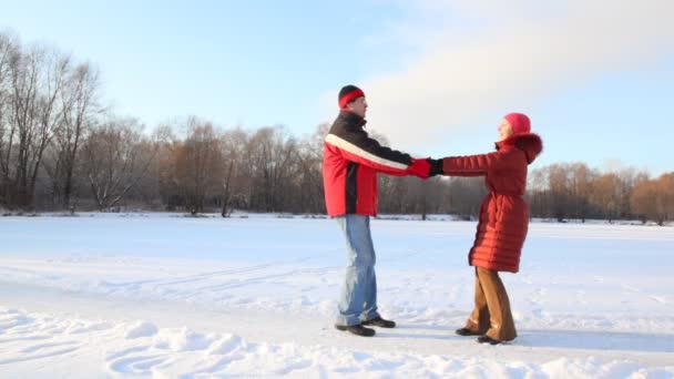 Pareja habiendo unido las manos gira en el campo de nieve — Vídeos de Stock