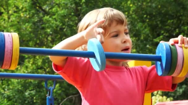 Девушка на детской площадке двигает колеса по трубе — стоковое видео