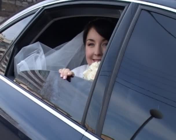 Mariée en robe de mariée se trouve dans la voiture et agite sa main — Video