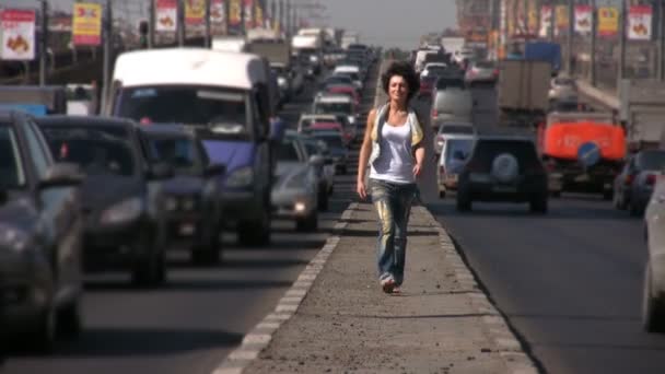 Дівчина приходить до камери на шосе посередині міста — стокове відео
