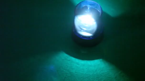 Блимач швидко обертається в темряві і освітлює підлогу під ним з яскравим світлом — стокове відео