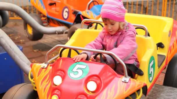Cute little girl sits in car park amusement — Stock Video