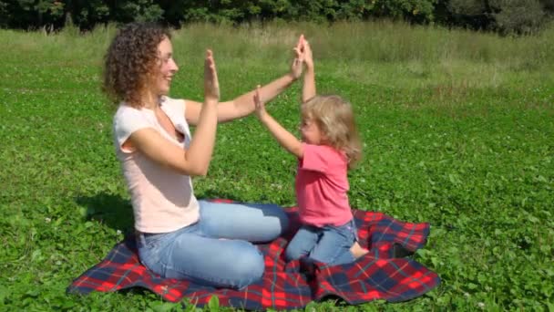 Moeder met daugher speelt pat-a-taart zit buiten in veld — Stockvideo