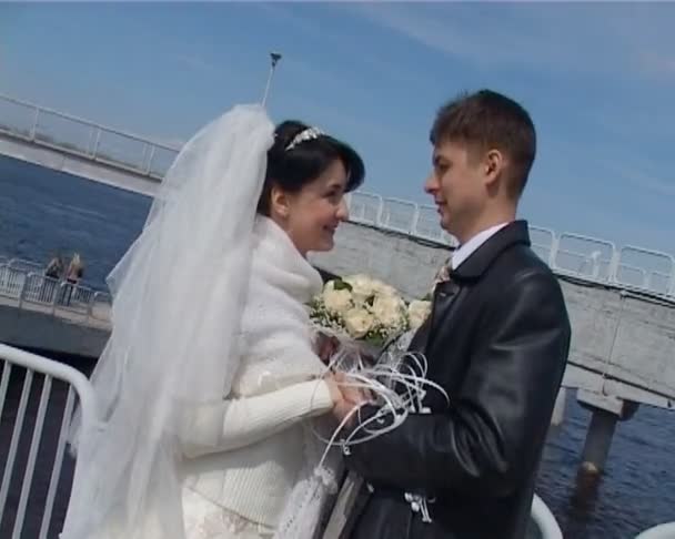 Bride and groom stands on bridge and looks at each other — Stock Video