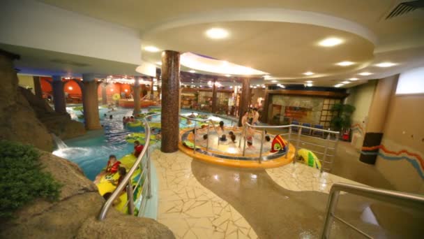 Jacuzzi mit Erwachsenen befindet sich in der Nähe des Pools, wo Kinder in Schwimmwesten schwimmen — Stockvideo