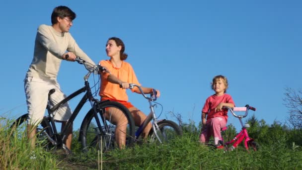 Família com filha senta-se em bicicletas e fala — Vídeo de Stock