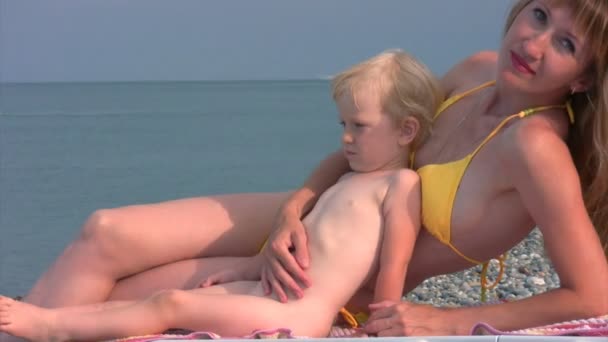 Mãe e pequena filha se senta na praia — Vídeo de Stock