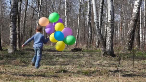 Boy with coloured balloons runs to spring forest from camera, then comes back — Stock Video