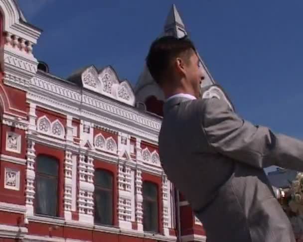 Bride and bridegroom rotating on red square — Stock Video