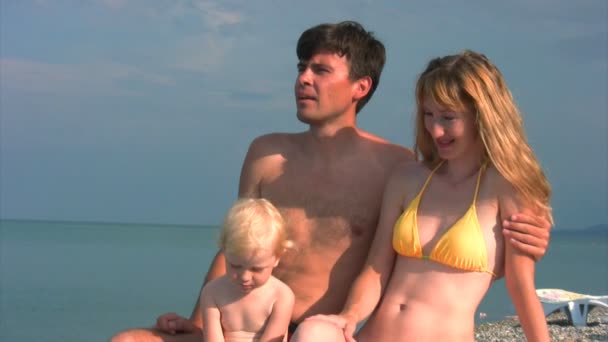 Семья с ребенком сидит на пляже — стоковое видео