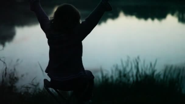 Kız sandalye ahşap gölet üzerinde oturuyor. — Stok video