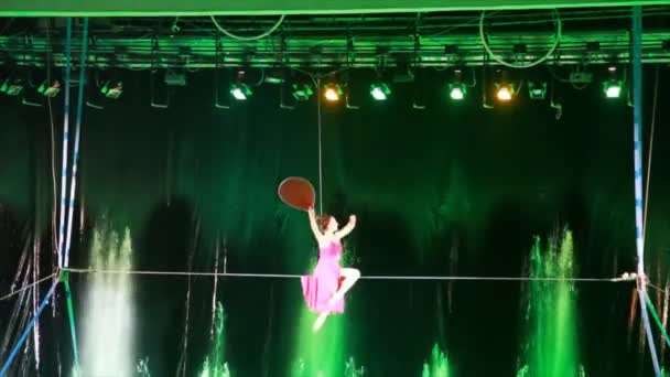 Tightrope walker with fan sits on wire, gets out of it, turns around and goes for it — Stock Video