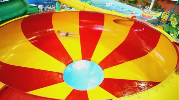 Fiú csúszik a kört a dombon, és dömpingelt lyuk aquapark — Stock videók