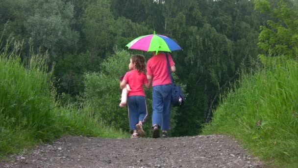 chlapec a dívka chodí na cestě z kamery v parku pod deštník