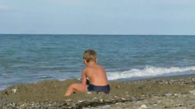 Çocuk sahil üzerinde bir delik dig.